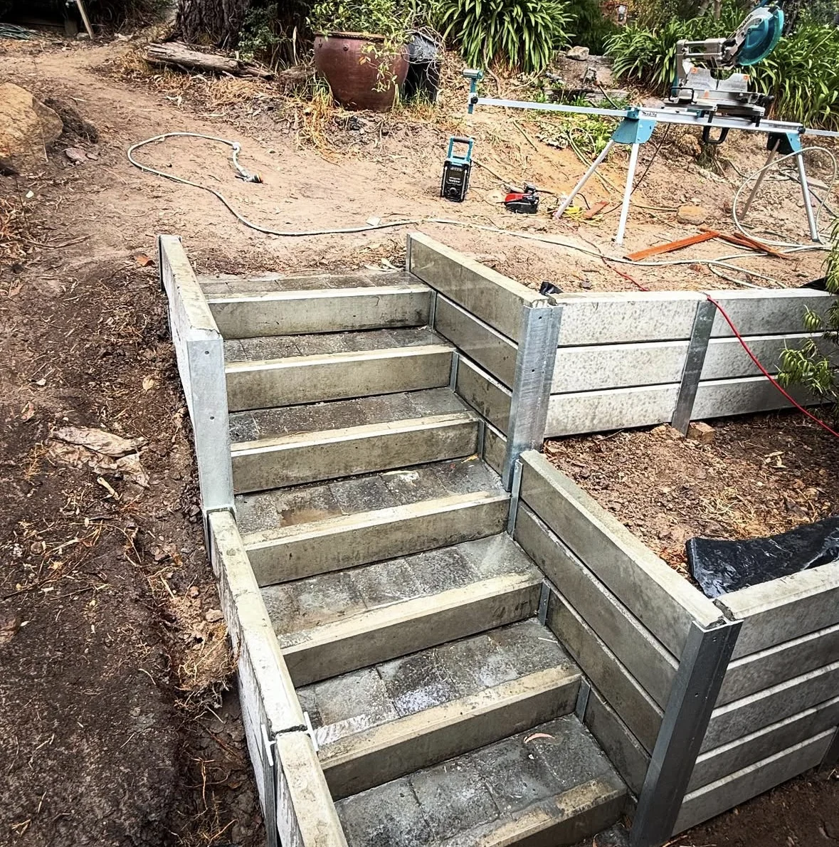 Concrete sleeper walls and a flight of garden steps under construction, showing how the levels connect
