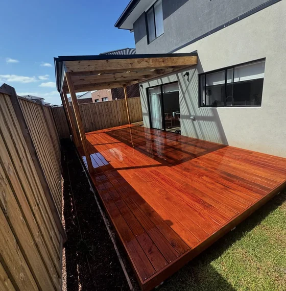 Timber pergola over a rich red timber deck beside a home
