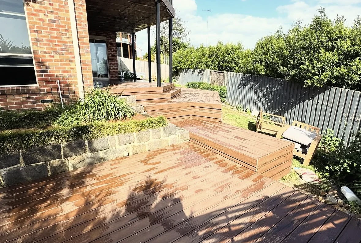 Timber terrace with broad stepped levels, established planting and a brick house